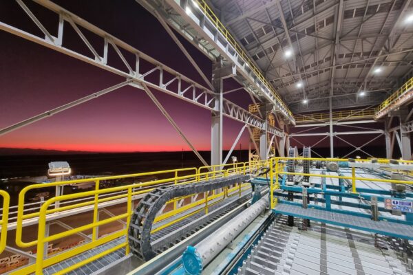 Una toma panorámica espectacular del filtro prensa GHT5000F Domino™ operando en una instalación minera de gran escala, con un ingeniero a su lado para proporcionar una perspectiva real de sus inmensas dimensiones y su robusta estructura de vigas superiores.