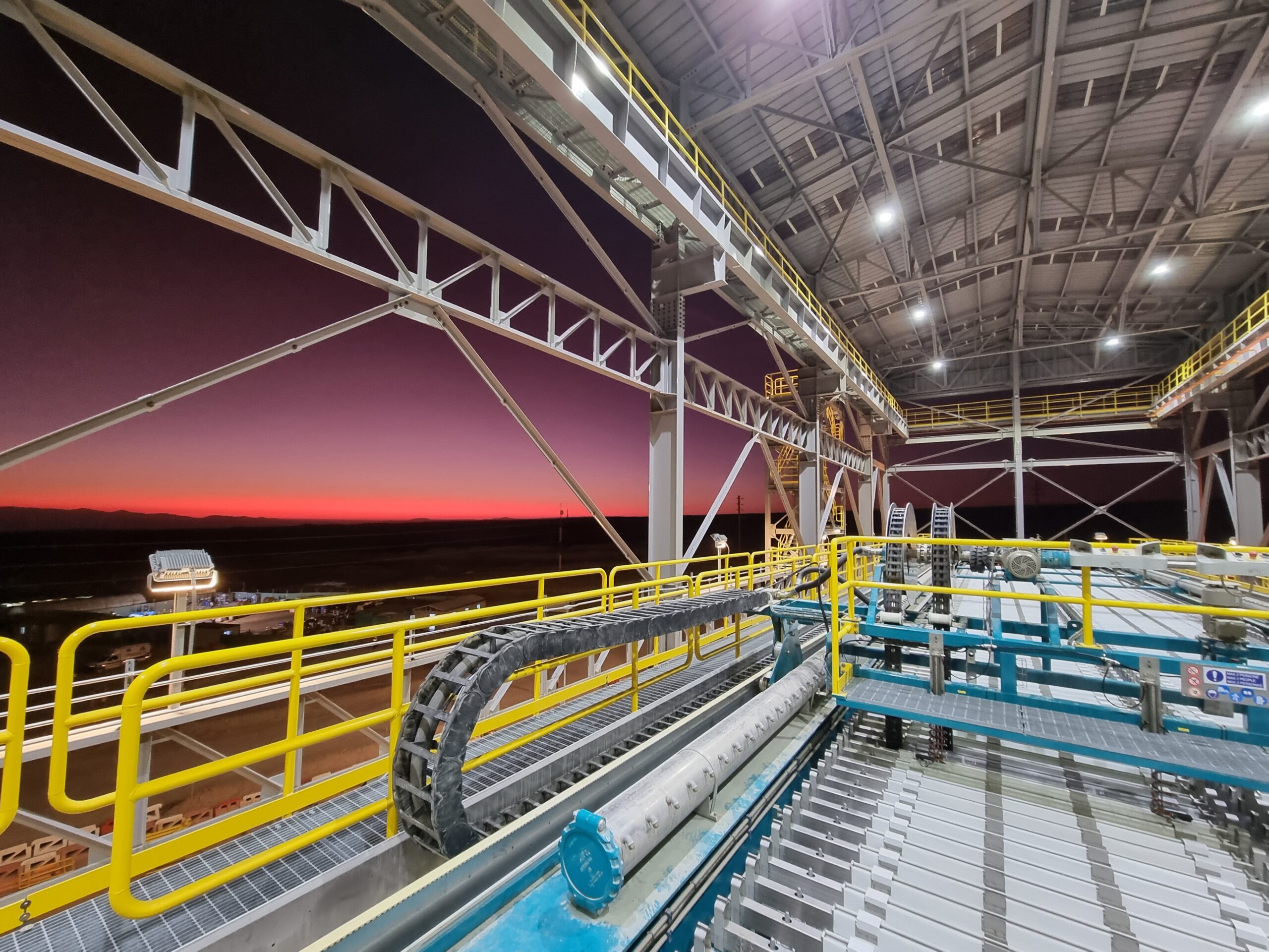 Una toma panorámica espectacular del filtro prensa GHT5000F Domino™ operando en una instalación minera de gran escala, con un ingeniero a su lado para proporcionar una perspectiva real de sus inmensas dimensiones y su robusta estructura de vigas superiores.